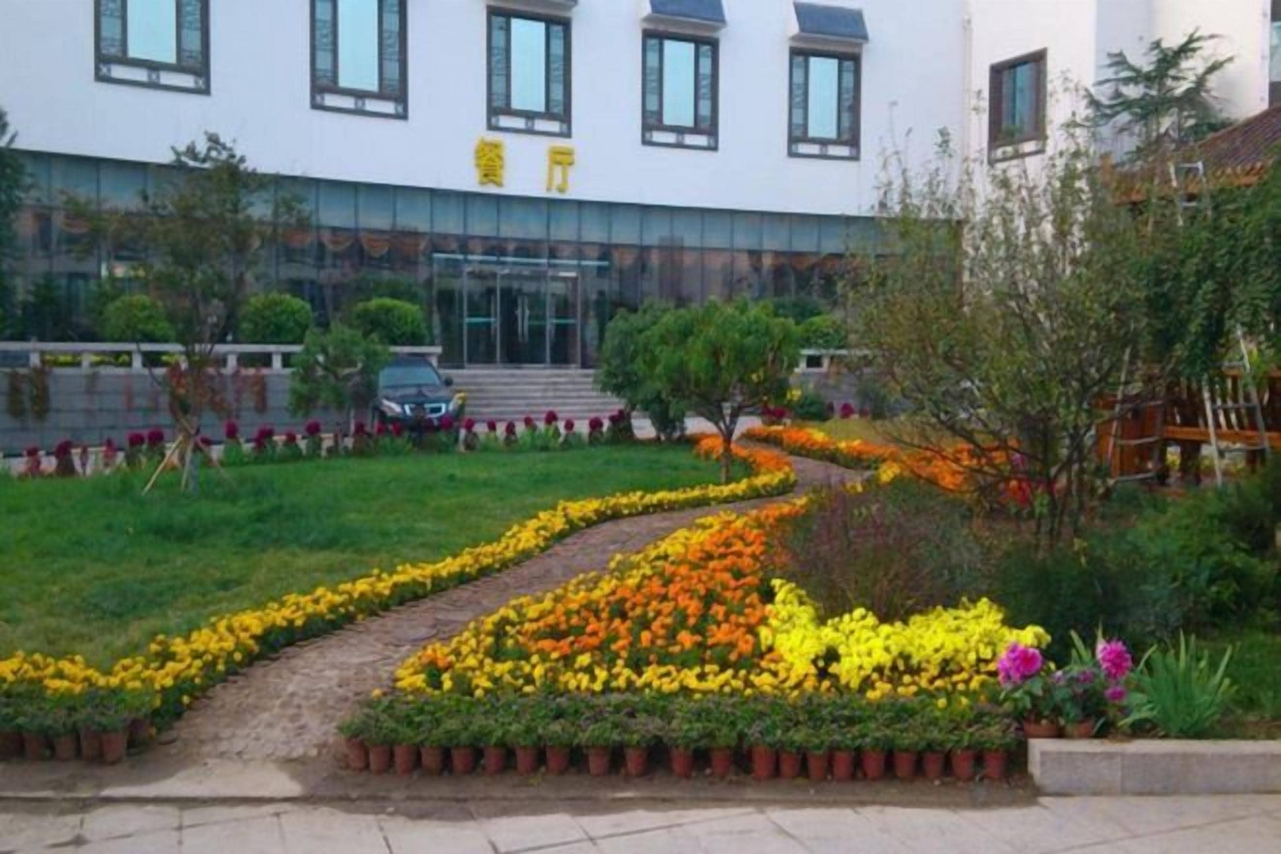 Un edificio con entrada pavimentada, un camino y un jardín de flores.