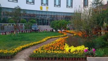 Un edificio con entrada pavimentada, un camino y un jardín de flores.
