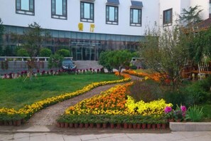 Un edificio con entrada pavimentada, un camino y un jardín de flores.