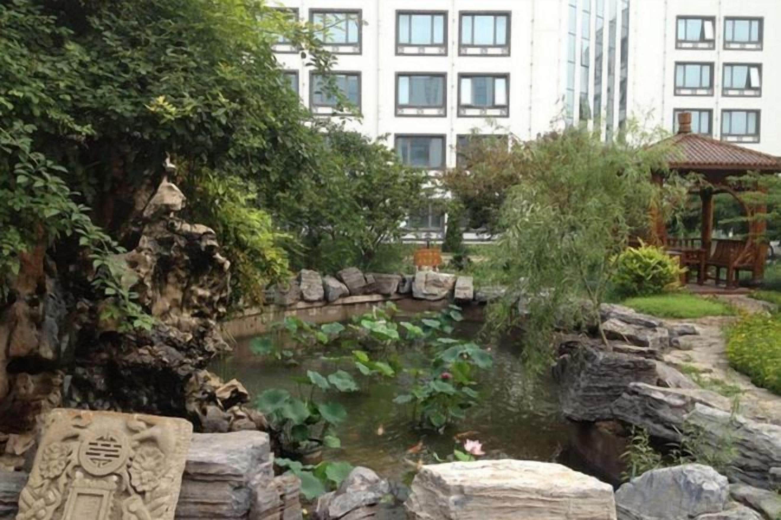 A landscaped garden with a pond, rocks, and a gazebo.