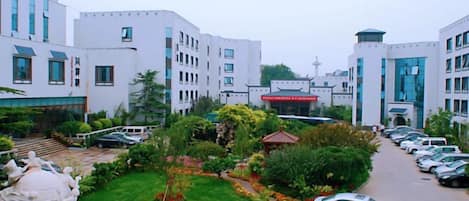 A hotel courtyard with a parking area, a central garden, and multiple buildings with a modern architectural style.