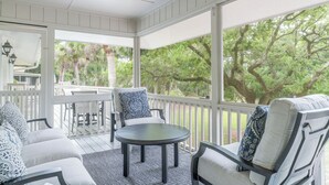 Une véranda aménagée avec des meubles d’extérieur, une table et une vue sur les arbres.