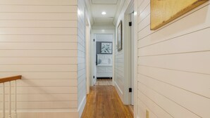 Un couloir doté d’un plancher en bois, de murs blancs et d’un escalier avec une rampe en bois.