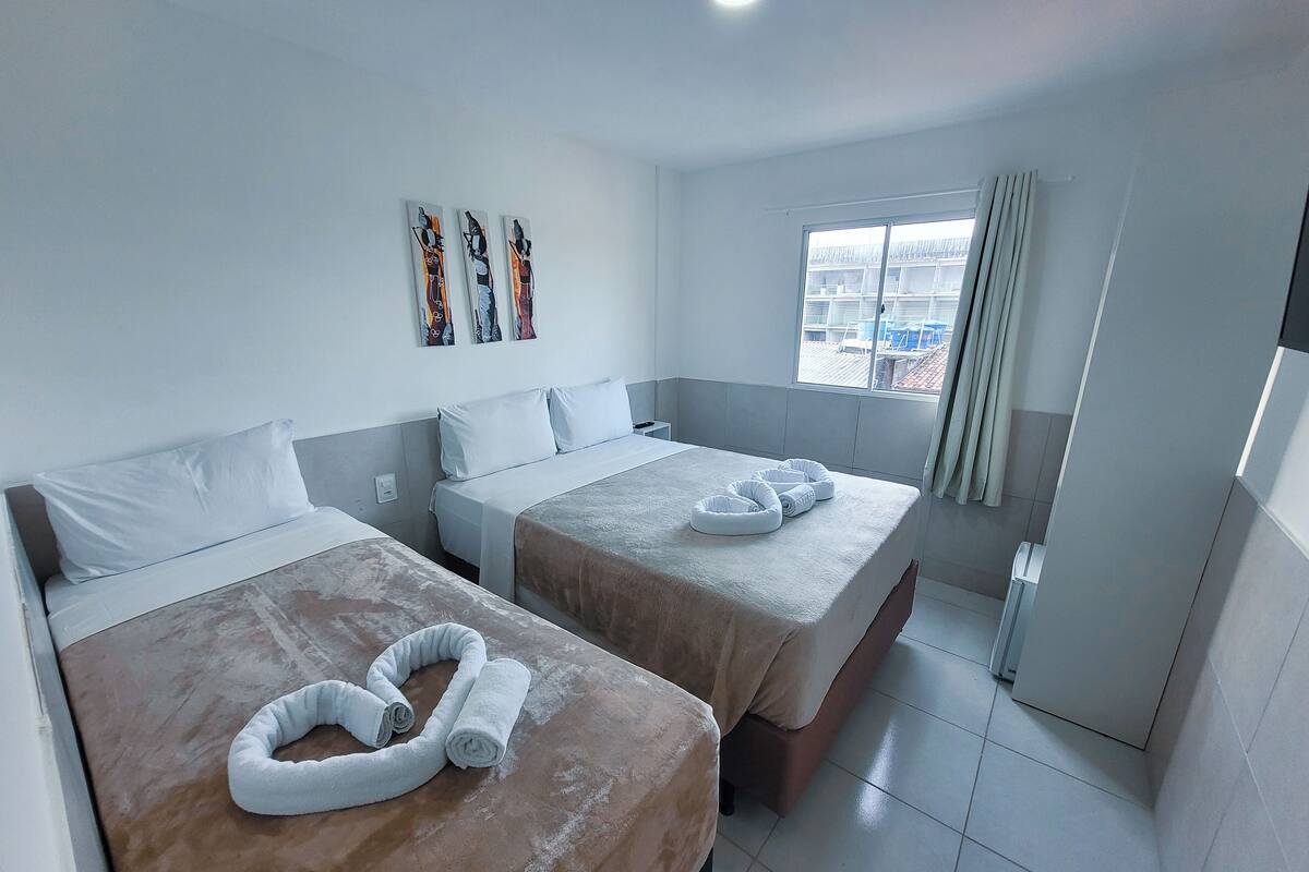 Habitació d'hotel amb dos llits, una finestra i vistes, i obra d'art a la paret.