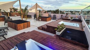 A rooftop terrace with wooden decking, seating areas, a hot tub, and a view of the cityscape. - Hotel Atlântico Sul (Ipojuca)