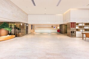 A spacious lobby with a reception desk, a large potted plant, and a modern elevator. - JI Hotel Shanghai Jinqiao International Comme (Shanghai)