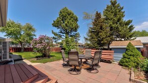 Eine Terrasse mit Tisch und Stühlen, umgeben von einer Holzterrasse und einem kleinen Baum.