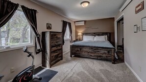 Ein Schlafzimmer mit Bett, Heimtrainer und einem Fenster mit Vorhängen.