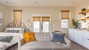 A modern bedroom with a bed, sofa, and a view of the outside.