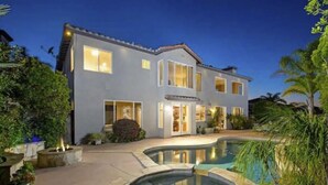 A two-story house with a swimming pool and a well-maintained garden.