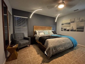 A bedroom with a bed, a chair, a nightstand, and a window with blinds. - Fully renovated home in Lake Mary (Lake Mary)