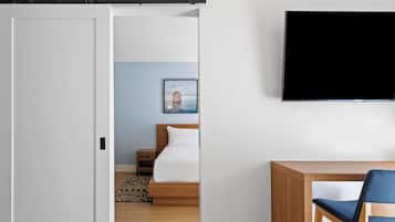 A hotel room with a bed, a desk, a chair, a TV, and a picture on the wall.