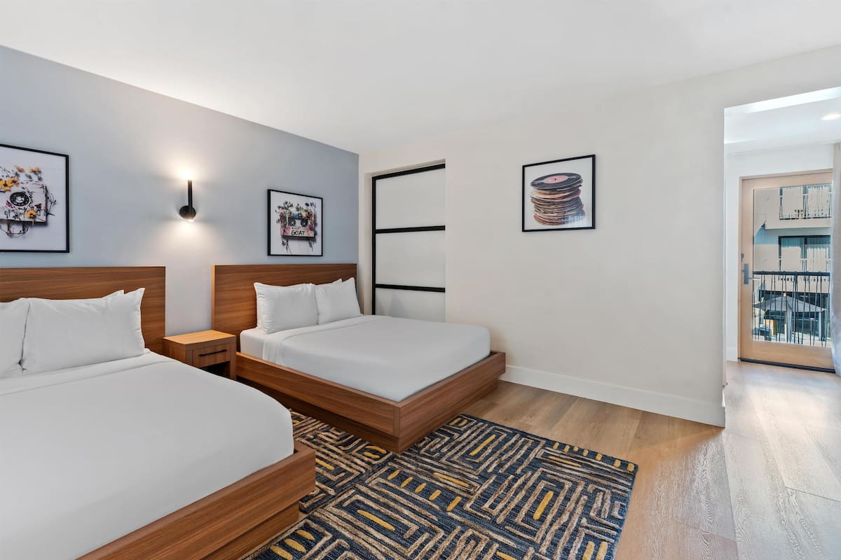 Una habitación de hotel moderna con dos camas, un tapete estampado y obras de arte en las paredes.