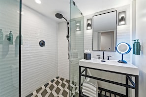 A modern bathroom with a glass-enclosed shower, a white sink with a mirror, and a black-framed vanity.