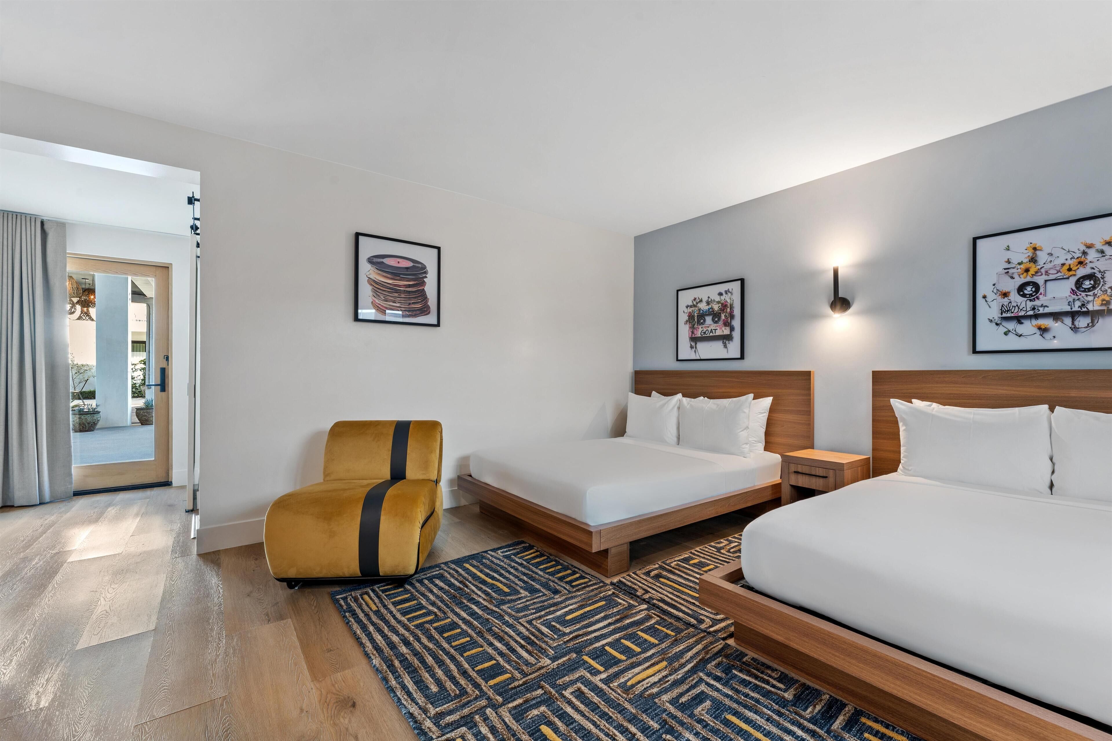 Une chambre d’hôtel comprenant un lit, une chaise, une table de chevet et un luminaire fixé au mur.