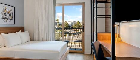 Una habitación de hotel con una cama, un escritorio y vista a la ciudad.