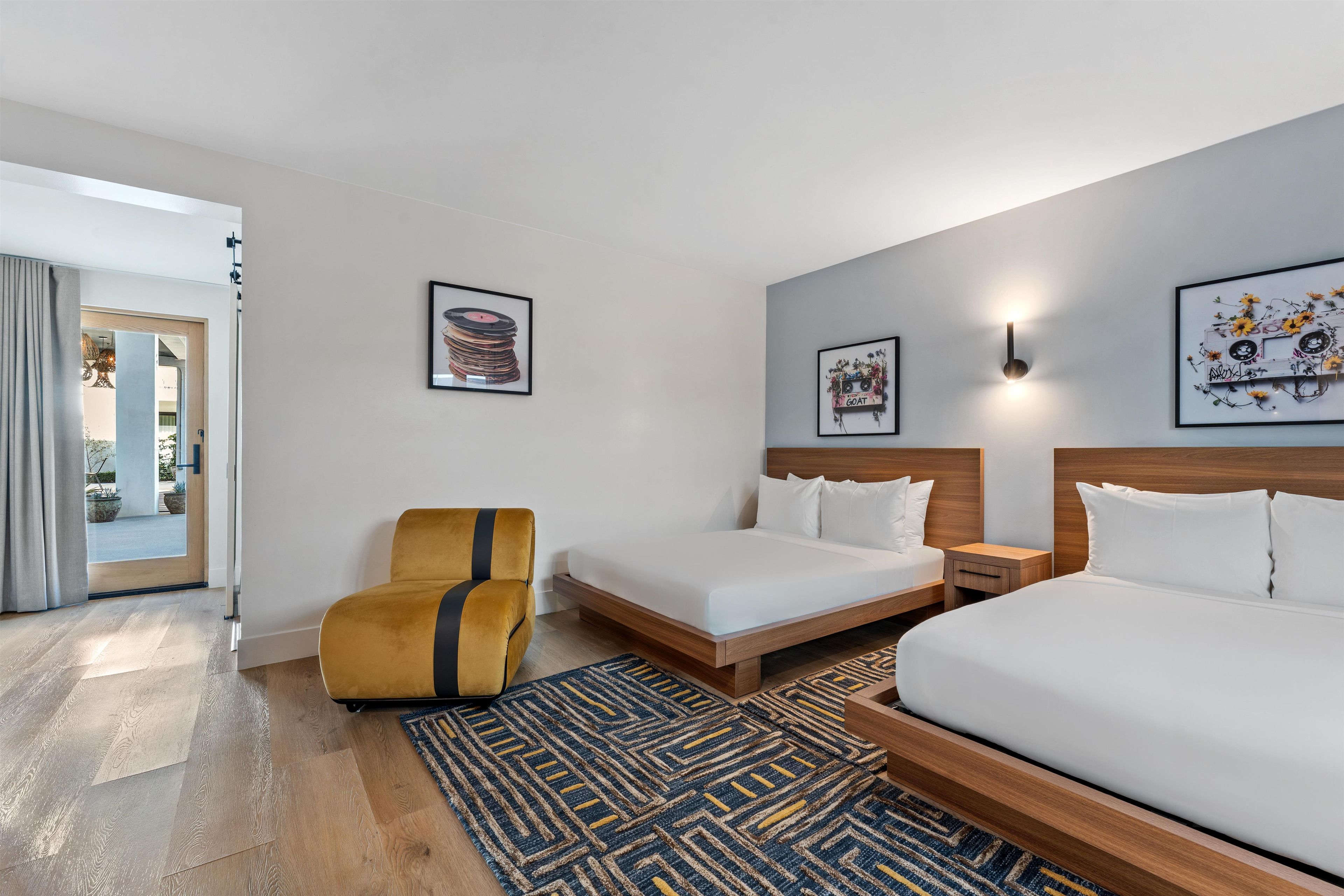 A hotel room with a bed, a chair, a nightstand, and two wall-mounted light fixtures.