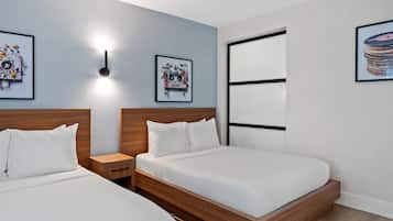 A modern hotel room with two single beds, a wooden headboard, a nightstand, and a wall-mounted light.