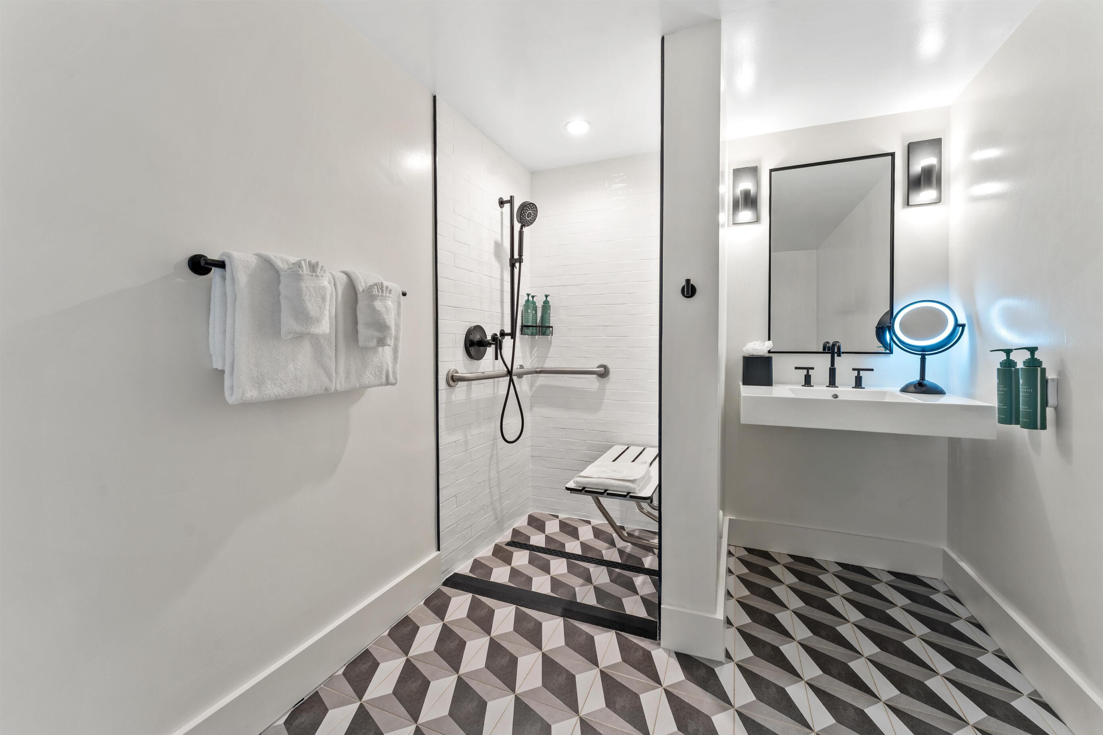 A modern bathroom with a shower, a sink with a mirror, and a towel rack.