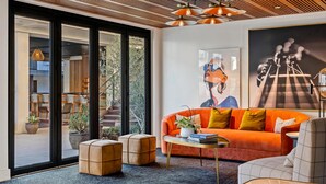 Una sala de estar moderna con un sofá grande color naranja, una mesa de centro redonda y vistas al área exterior a través de puertas correderas de vidrio.