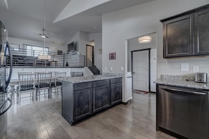A modern kitchen with dark cabinets, a granite countertop, and stainless steel appliances.