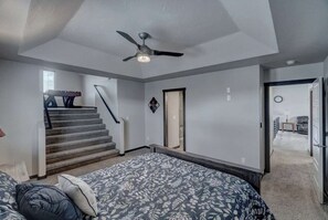 Ein Schlafzimmer mit einem Bett, einem Deckenventilator, einer Treppe und einer Tür zu einem anderen Raum.