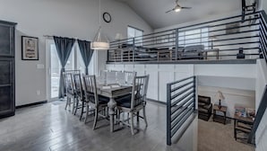 A spacious dining area with a high ceiling, a staircase leading to an upper level, and a view of the outdoors through large windows. - Convenient Location Family-Friendly Locally Owned (Rapid City)