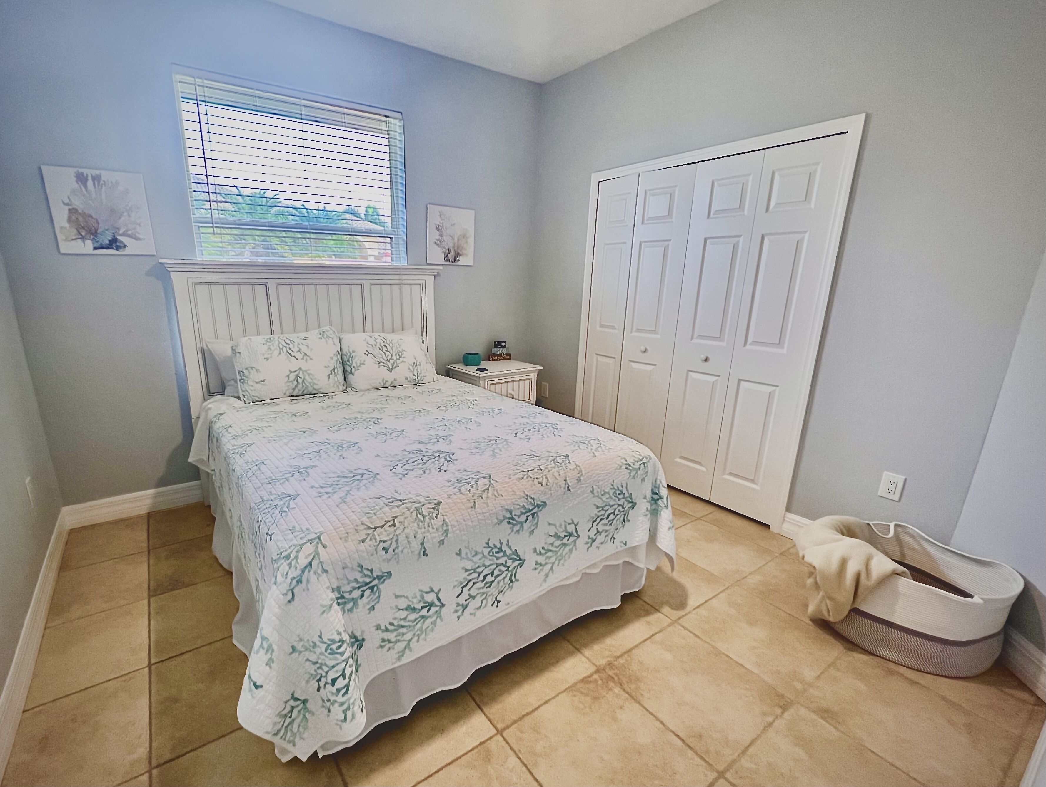 A bedroom with a bed, a window, a wardrobe, and a small bedside table.
