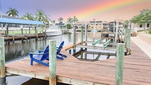 Un quai avec un bateau, des chaises en bois et une marina avec des bâtiments en arrière-plan.