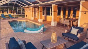 Un espace extérieur abrité avec une piscine, des chaises longues et une table à manger.