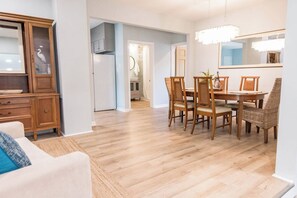 Un salon spacieux avec une table et des chaises en bois, un grand buffet et une vue sur la cuisine.