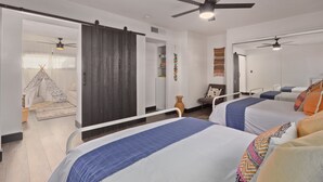Une chambre d’hôtel moderne avec deux lits, un grand miroir, un ventilateur de plafond et une porte coulissante donnant sur un balcon.