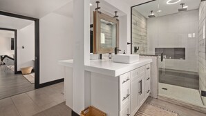 Une salle de bain moderne avec un meuble-lavabo blanc, un grand miroir et une douche séparée par des parois en verre.