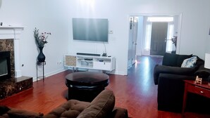 Uma sala de estar com lareira, televisão de tela plana, sofá e mesa de centro.