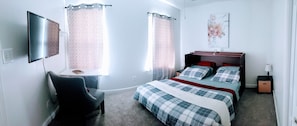 Un dormitorio con cama, una silla, un escritorio y un televisor.