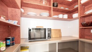 A kitchen with wooden shelves, a microwave, and various kitchen items. - Slick Home, Free Parking (Brunswick)