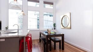 A modern kitchen with a central island, red bar stools, a dining table, and large windows. - Slick Home, Free Parking (Brunswick)
