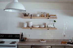 Modern kitchen with stove, stainless steel oven, and pendant light.