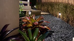Un jardin avec un sentier, des plantes et une clôture décorative.