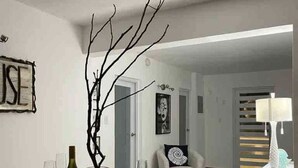 Un coin repas avec une table sombre, dressée pour le repas, une bouteille de vin et une branche décorative.