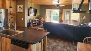 A modern kitchen with a central island, wooden cabinets, and a built-in dishwasher.