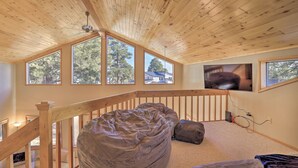 Ein geräumiges Schlafzimmer im Loft-Stil mit hoher Decke, großen Fenstern, einer Holztreppe und einem gemütlichen Sitzsack.