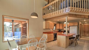 Eine moderne Küche mit Holzausstattung, ein Essbereich mit weißen Stühlen und ein Balkon mit Holzgeländern.