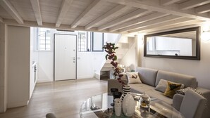 Un salon moderne avec une table basse en verre, un canapé et un escalier menant à un niveau supérieur.