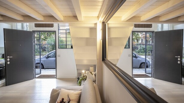 Un intérieur moderne avec un canapé, un miroir et une vue sur les voitures garées à l’extérieur.