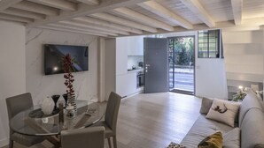 Un salon moderne avec une table à manger en verre, un canapé et un téléviseur fixé au mur.