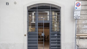 Une entrée d’immeuble avec un portail en métal, un panneau indiquant qu’il est interdit de se garer et un panneau portant le chiffre 8 sur le mur.