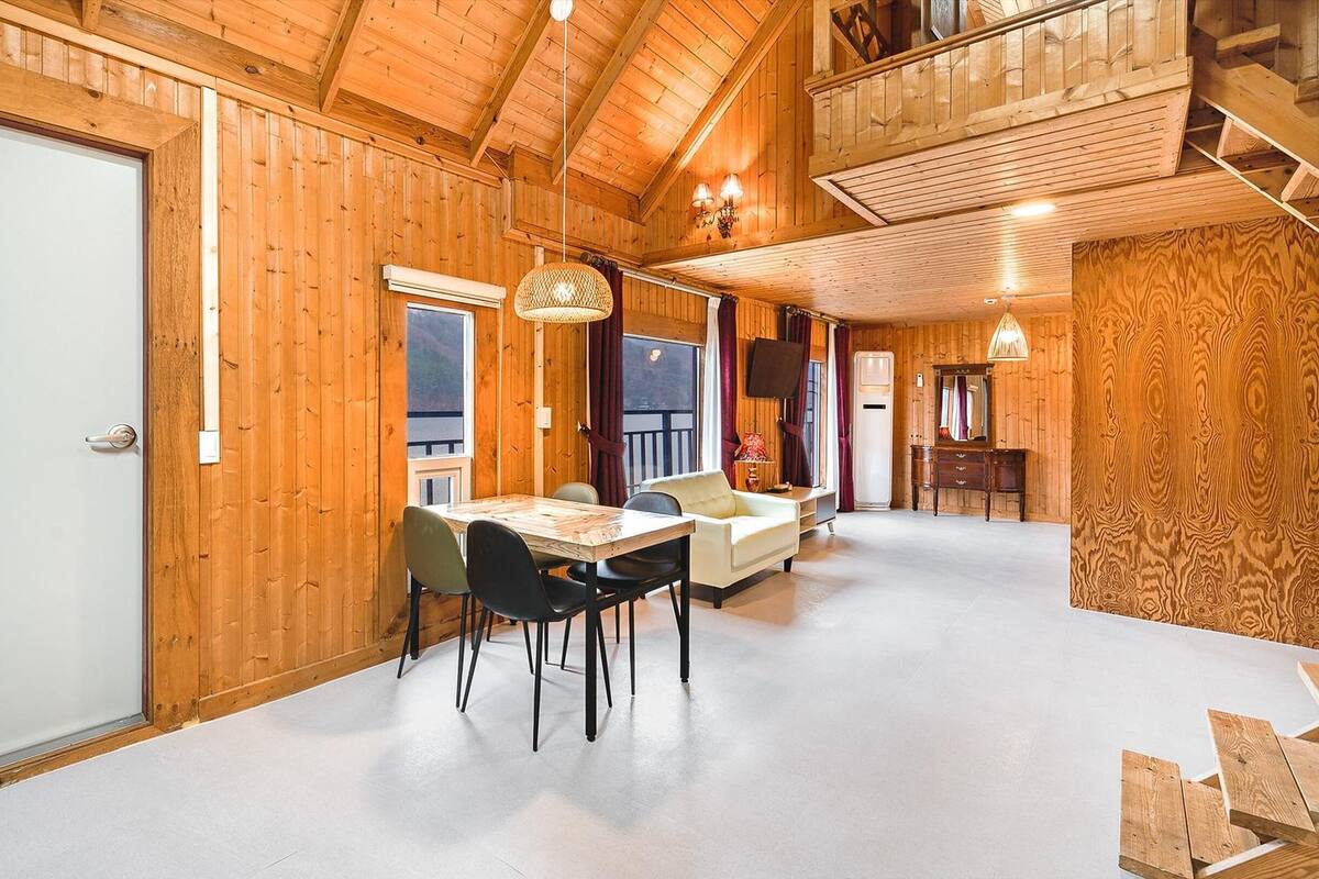 Un interior de madera con comedor, televisor y balcón.