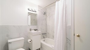 Een badkamer met toilet, wastafel, spiegel, douche en bad.