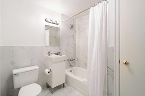 Un baño con inodoro, lavamanos, espejo, ducha y bañera.